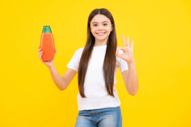 Child with shampoo conditioner. Daily cosmetic care. Teenager hold bottle of hair and skin care. Beauty health and cosmetics. Happy teenager portrait. Smiling girl