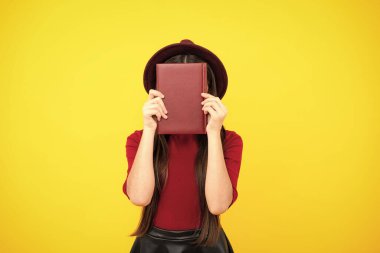 Kopya kitabı olan liseli kız izole edilmiş arka planda poz veriyor. Edebiyat dersi, ilkokul. Entelektüel çocuk okuyucu