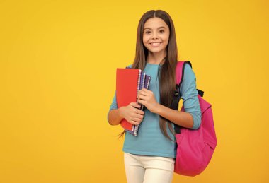 Mutlu ergen portresi. Liseli kız, genç kız, sarı izole stüdyo geçmişi üzerine kitap tutuyor. Okul ve eğitim kavramı. Okula dönelim. Gülümseyen kız