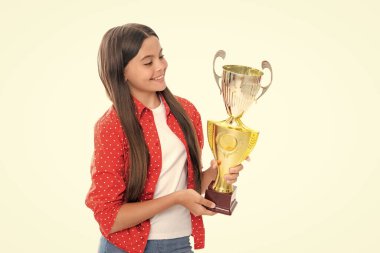 Elinde kupa tutan genç bir kız. Kazanan çocuk, başarıyı ve zaferi kutlayarak yarışmayı kazandı. Mutlu gülümseyen genç kız portresi beyazlar içinde izole edilmiş.
