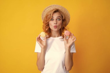 Kurabiye yiyen bir kadın. Yazın hasır şapkalı, tatlı badem kurabiyesi yiyen güzel kızıl saçlı kadın. Fransız tatlısı, tatlılar.