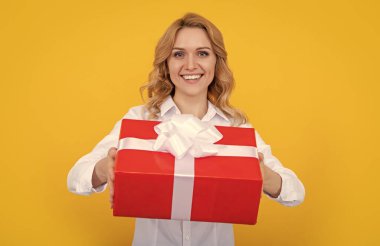 Sarı arka planda büyük hediye kutusu olan neşeli bir kadın..