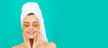 Genç bayanın yüzünde havluyla kolajen altın göz bandı olmasına sevindim. Güzel kadın, izole edilmiş yüz portresi, taklit alanı olan pankart.