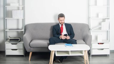 İş adamı ofisinde oturuyor ve telefonda konuşuyor..