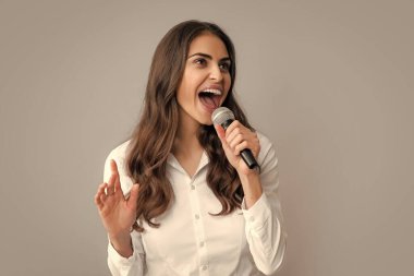 Young pretty woman singing a song with a microphone, presenting an event or having a party. Happy singing girl