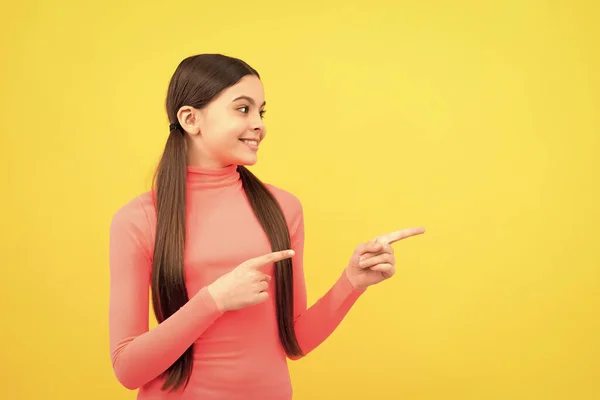 発表だ 買い物の販売と割引 提案してくれ 商品提案だ 明るい子はコピースペースで指を指してる 黄色の背景に可愛い10代の女の子の広告 幸せな子供の肖像画 — ストック写真