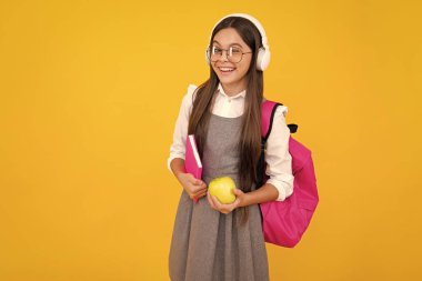 Okul üniformalı kız elma tutuyor. Okul ve eğitim kavramı. Okula dönelim. Öğrenci, ders çalışan genç bir öğrenci. Mutlu yüz, pozitif ve gülümseyen genç kız duyguları