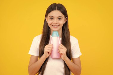 Genç kız şişe şampuanı ya da duş jeli gösteriyor. Saç kozmetik ürünü. Reklam için şişe fotokopi alanı oluşturun. Mutlu ergen portresi. Gülümseyen kız