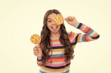 Yüz ifadeleri. Mutlu kız lolipopu beyazın üzerinde izole halde tutuyor. Lolipop çocuk. Renkli süveter giyen çocuk lolipopu tutuyor. Çubukta şeker. Şekerci. çocukluk. Genç diş bakımı. Tatlı düşkünü. Lezzetli.