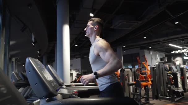 運動選手はフィットネスジムでランニングマシンで運動します ジムのフィットネストレッドミルでジョギングする男にフィットします トレッドミルのトレーニング 心臓ジムのトレーニング フィットネス練習 — ストック動画