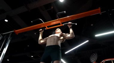 Yüksel. Spor salonunda barfiks antrenmanı yapan güçlü bir atlet. Sporcu barfiks egzersizi yapar. Sporcu spor salonuna gidiyor..