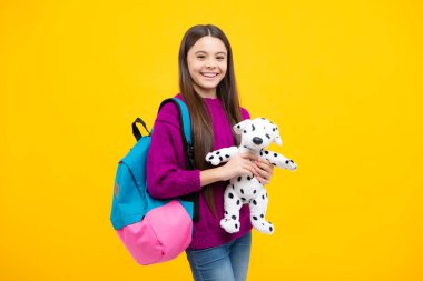 Schoolgirl 12, 13, 14 years old with toy. School children cuddling favorite toys on yellow background. Happy childhood