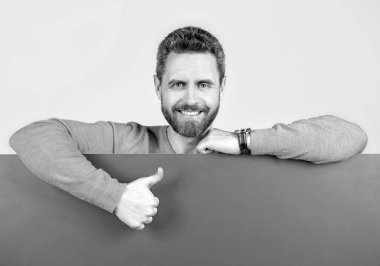 Yenilik bilgisi sunuyorum. Pembe kağıdın arkasındaki erkek baş parmağını kaldırıyor. Reklam için fotokopi alanı olan mutlu bir adam. Reklamcılık. Duyuru. Alışveriş ve indirim. ürün sunumu.