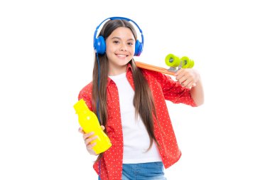 Modayı takip eden genç modelin gündelik görüntüsü. Genç yeniyetme hippi şehir hayatı. Kaykaylı ve kulaklıklı sokak tarzı bir kız çocuğu.