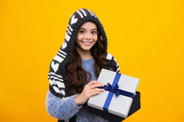 Funny kid girl in winter wear holding gift boxes celebrating happy New Year or Christmas. Winter holiday. Happy teenager, positive and smiling emotions of teen girl
