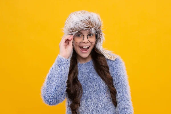 漂亮的少女戴着冬帽和一件暖和的毛衣 一个在黄色孤立背景上的孩子 年轻女孩激动的脸 快乐的情绪 — 图库照片