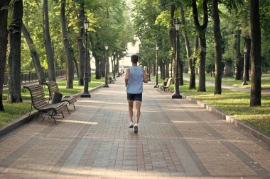 Spor kıyafetleri içinde koşan atletik bir adamın arka görüntüsü..