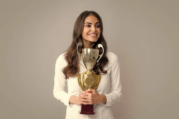 一个快乐的女商人站在灰色的背景下 举着奖杯 成功的员工会拿起优胜杯 获奖者的颁奖典礼 最佳经理 — 图库照片