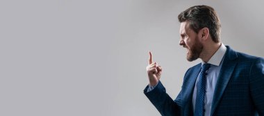 Resmi kıyafetli kızgın komisyoncu parmağını kaldırmış gri arka plan fotokopi alanı, öfke içinde tutar. İnsan yüzü portresi, fotokopi alanı olan pankart. Takım elbiseli bir iş adamı, izole stüdyo geçmişi var.