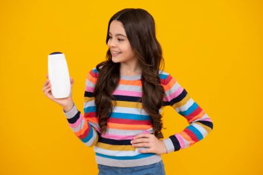 Şampuan kremi kullanan bir çocuk. Günlük kozmetik bakım. 12, 13, 14 yaşlarındaki ergen çocuğun elinde saç ve cilt bakımı şişesi var. Güzellik sağlığı ve kozmetik ürünleri. Mutlu genç