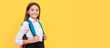 Okul üniformalı gülümseyen genç kız sırt çantası taşıyor, bilgi günü. Öğrenci portresi, stüdyo afişi. Okul çocuğu yüzü, boşluklar