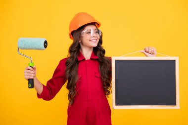 Kasklı, fırçalı çocuk ressamı. Kasklı çocuk. İnşaat alanında boyacı çocuk. Yenileme ve onarım. Genç kızın mutlu gülümseyen duyguları