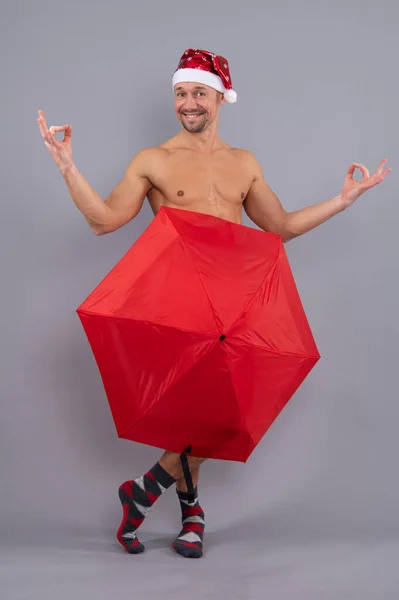 疯狂的裸体桑塔覆盖内裤与伞 赤裸裸的同性恋桑塔在灰蒙蒙的工作室背景下的滑稽姿势 — 图库照片