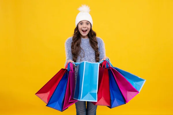 漂亮的少女 戴着冬暖的帽子 背着黄色背景的购物袋 购物和时尚的购物狂 带着购物袋的小孩兴奋的脸 — 图库照片
