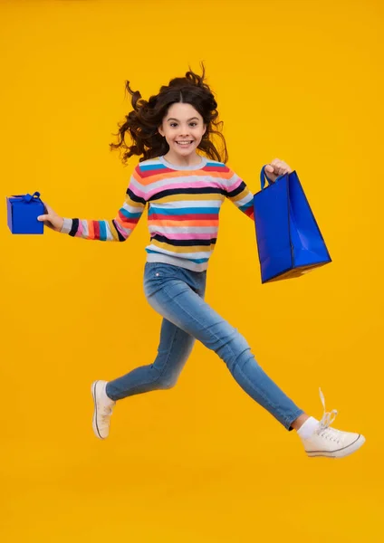 小女孩拿着购物袋 享受着黄色背景的独立销售 少女的画像准备去买东西了 跑啊跳啊 — 图库照片