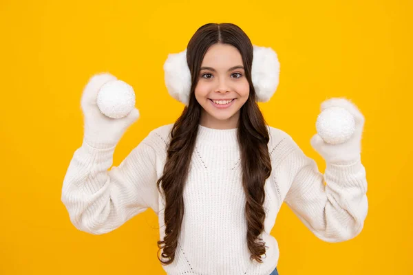ポートレートのティーン子供女の子身に着けていますニット手袋と冬のセーター遊びますクリスマスボール孤立した上の黄色のスタジオの背景 — ストック写真