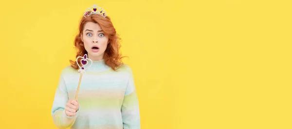 surprised redhead woman in queen crown with magic wand, surprise. Woman isolated face portrait, banner with copy space