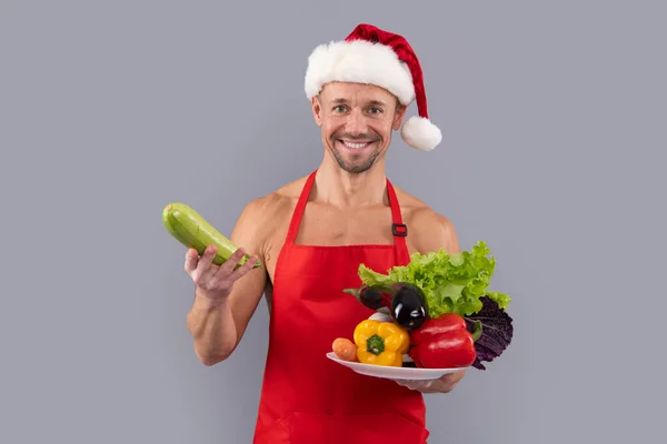 圣诞老人素食主义者年轻男子蔬菜灰色工作室背景 快乐有趣的桑塔做健康的饭菜 圣诞节或新年健康的素食 — 图库照片