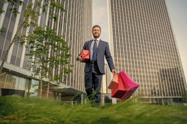 Hediyeli kutusu olan yakışıklı bir adam. CEO doğum günü hediyesi taşıyor. Adam alışveriş torbalarını tutuyor. Erkekler günü. Paketleri olan mutlu bir iş adamı. Satış ve indirim. Ona sürpriz yapacağım. Sevgilim olur musun? Boks günü.