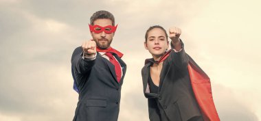 Gökyüzü geçmişinde süper kahraman kıyafeti giyen cesur iş çifti.