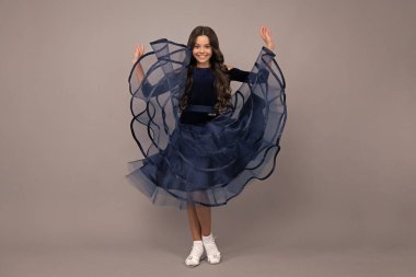 Full length of teenager child wearing ball dress. Movement dress of young child teen girl. Happy girl face, positive and smiling emotions