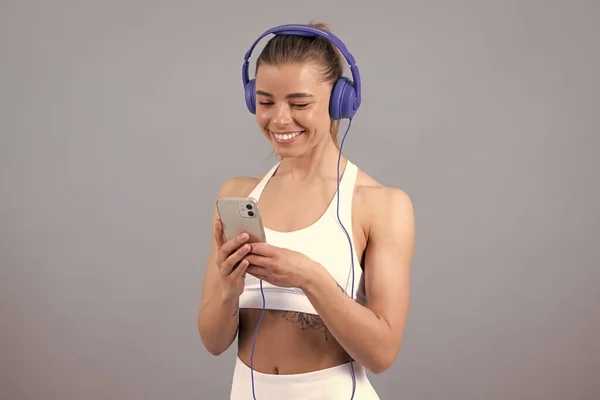 소녀는 취미로 음악을 전화를 사용하면서 이어폰으로 음악을 스포츠 — 스톡 사진
