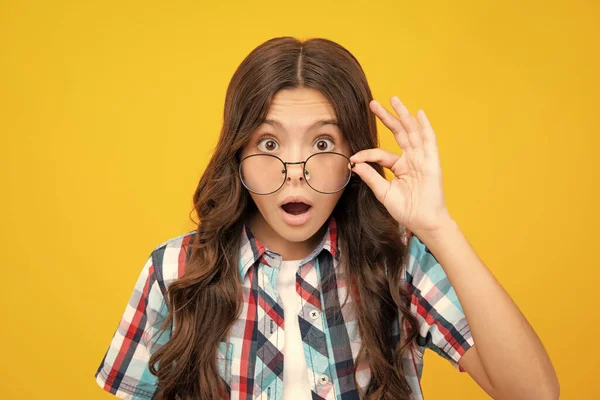 stock image Shocked surprised teenager girl. Teenager child wearing glasses on yellow studio background. Cute girl in eyeglasses