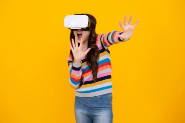 Sanal gerçeklik kaskı takmış genç bir kızın portresi, sarıda izole edilmiş. Oyuncu VR oyunları, VR oyunları oynuyor. Şaşırmış yüz, şaşırmış genç kız duyguları.