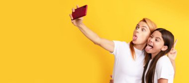 Anne ve kız çocuk afişi, kopyalama alanı, izole bir arka plan. Komik kadın ve kız cep telefonuyla selfie çekiyorlar. Selfie ailesi. Modern hayat. mobil teknoloji