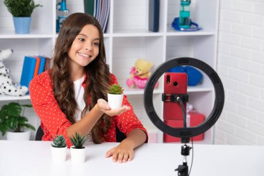 Young blogger girl recording video for blog. Teen girl speaking in front of camera for vlog. Teenager working as blogger, recording video tutorial for blog. Happy girl , positive and smiling emotions