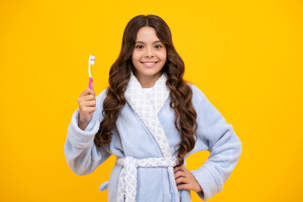 Morning brushing teeth. Teenager girl brushing her teeth over isolated yellow background. Daily hygiene teen child hold toothbrush, morning routine. Dental health oral care