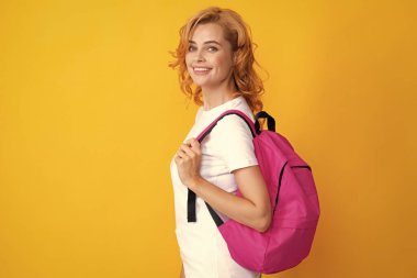 Sırt çantalı, heyecanlı, kızıl saçlı genç bir kız öğrenci. Sarı arka planda stüdyo eğitimi almış. Lise üniversitesinde okumuş.