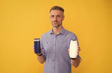 Sarı arka planda şampuan şişesi gösteren bir adam..