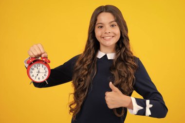 Teen girl 12, 13, 14 years old look at alarm clock. Time for shopping sales. Good morning, checking time