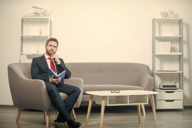 Takım elbiseli olgun bir adam ofiste planlamacıyla oturuyor..