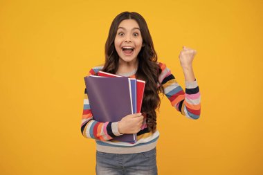 Amazed teenager. Back to school. Teenager schoolgirl with book ready to learn. School girl children on isolated yellow studio background. Excited teen girl