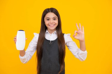 Şişe şampuanı ya da duş jeli olan ergen bir kız. Çocukların saç bakımı. Saç makyaj ürünü, şampuan şişesi.