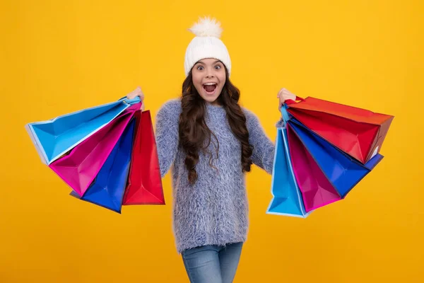 Stock image Teenager child girl in winter warm hat hold shopping bag enjoying winter sale. Autumn shopping sale. Child girl is ready to go shopping. Excited face, cheerful emotions of teenager girl