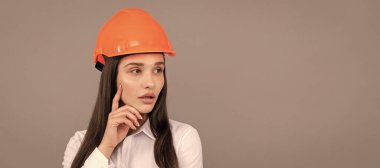 Güvenlik kasketi ve gri arka planda beyaz gömlekli düşünceli bir kadın, müteahhit. İzole edilmiş yüz portresi, taklit alanı olan pankart