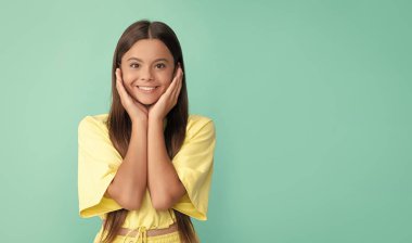 cheerful teen girl with long hair on blue background, portrait.